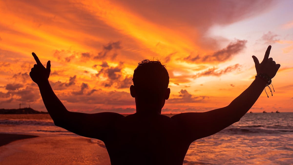 Silhouette of a person enjoying a vibrant sunset on the beach in Lima, Perú.